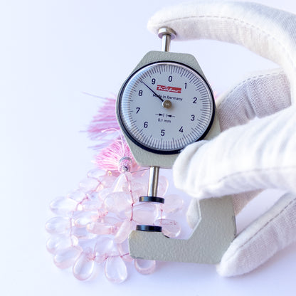 A dial gauge measures the Rose Quartz smooth briolette 8–8.7mm gemstone.