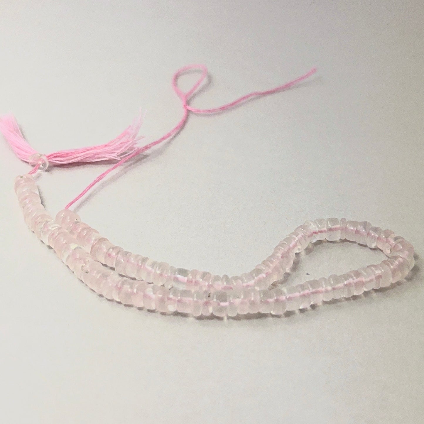 Rose Quartz smooth wheel beads aligned on a strand, highlighting colour, clarity and quality stone beads.