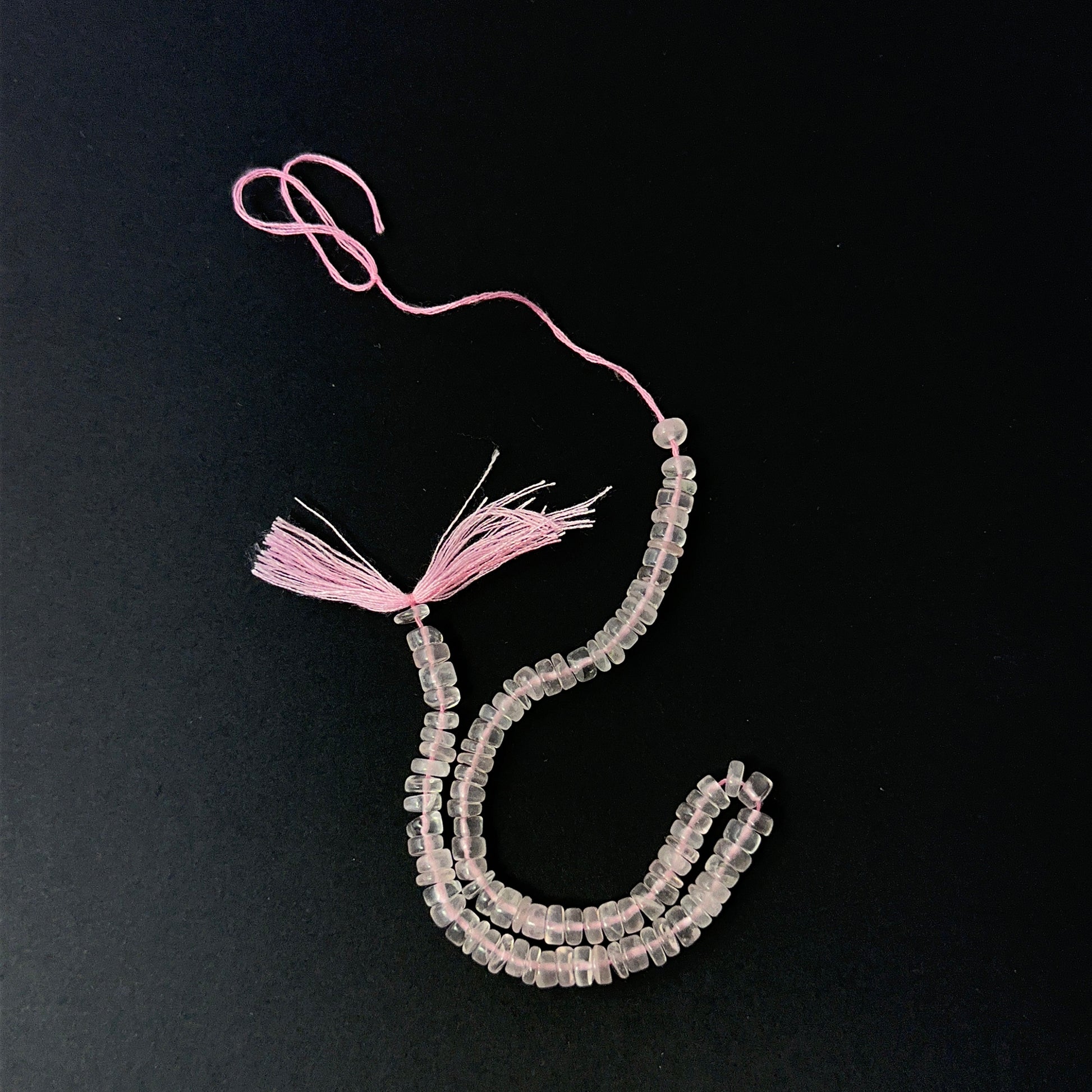 Close view of polished Rose Quartz smooth wheels arranged on a 21cm strand for handmade jewellery components.