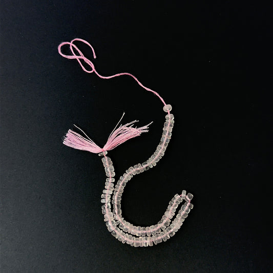 Close view of polished Rose Quartz smooth wheels arranged on a 21cm strand for handmade jewellery components.
