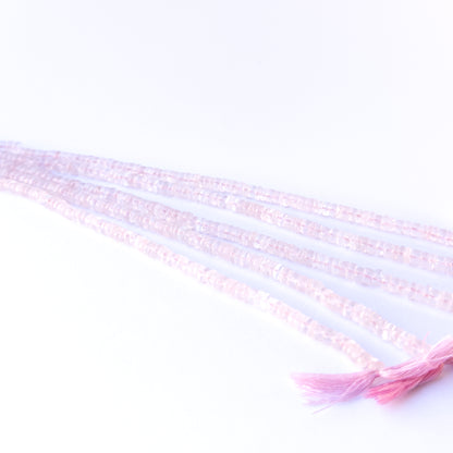 A person holds delicate strands of Rose Quartz beads, showcasing their smooth wheel design.