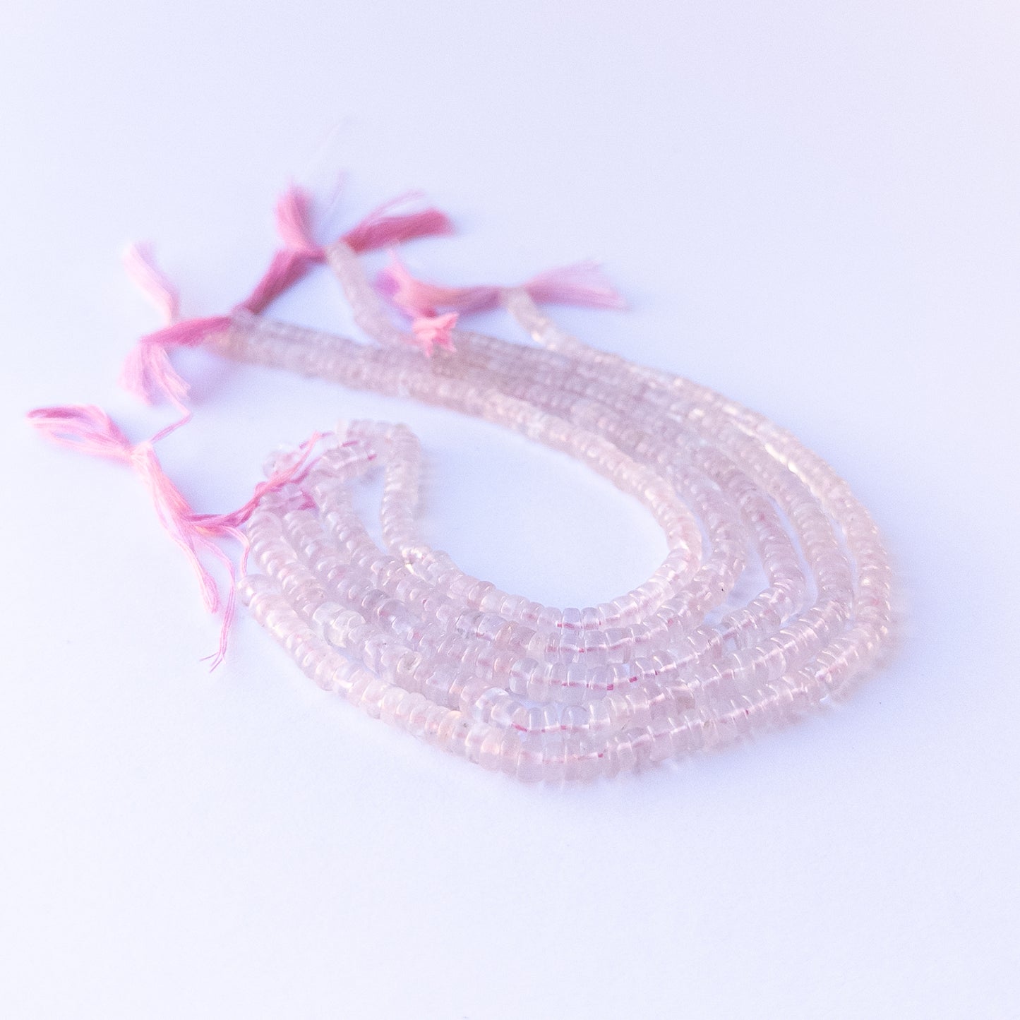 Handmade jewellery components featuring natural rose quartz smooth wheels with soft tones and polished glow.