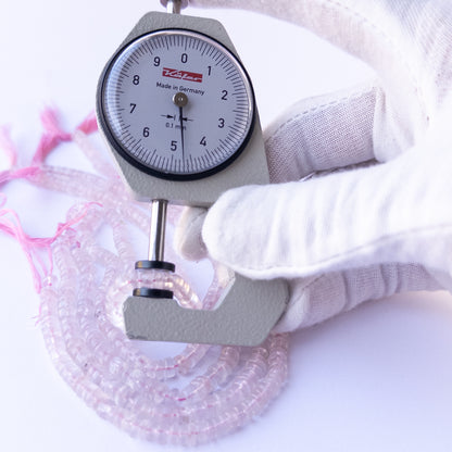 A dial gauge measures the Rose Quartz smooth wheel 4.5–5mm gemstone.