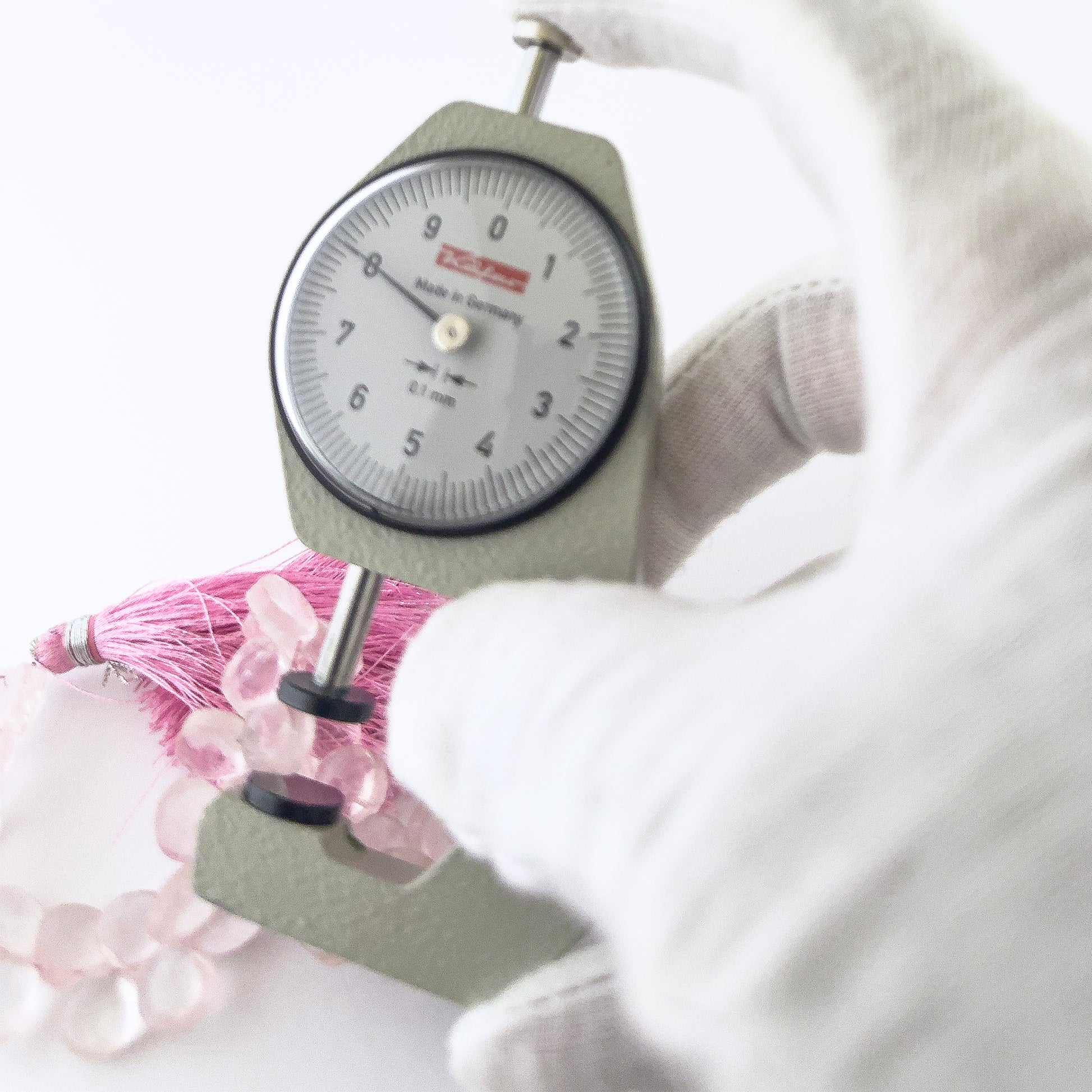 A dial gauge measures the Rose Quartz faceted briolette 8–8.5mm gemstone.