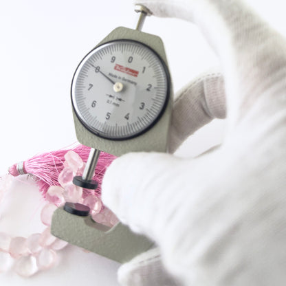 A dial gauge measures the Rose Quartz faceted briolette 8–8.5mm gemstone.