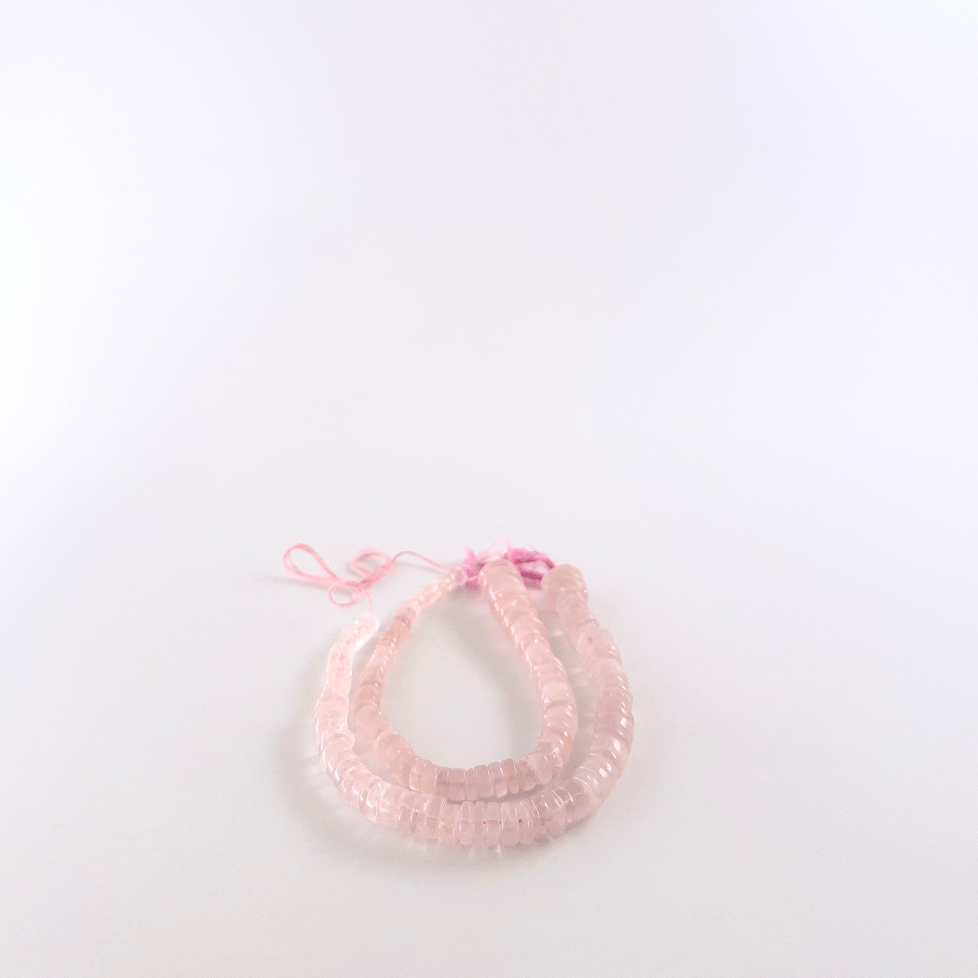 Rose Quartz wheel beads featuring smooth surfaces and a wide 5.5–12mm size gradient for a textured look.