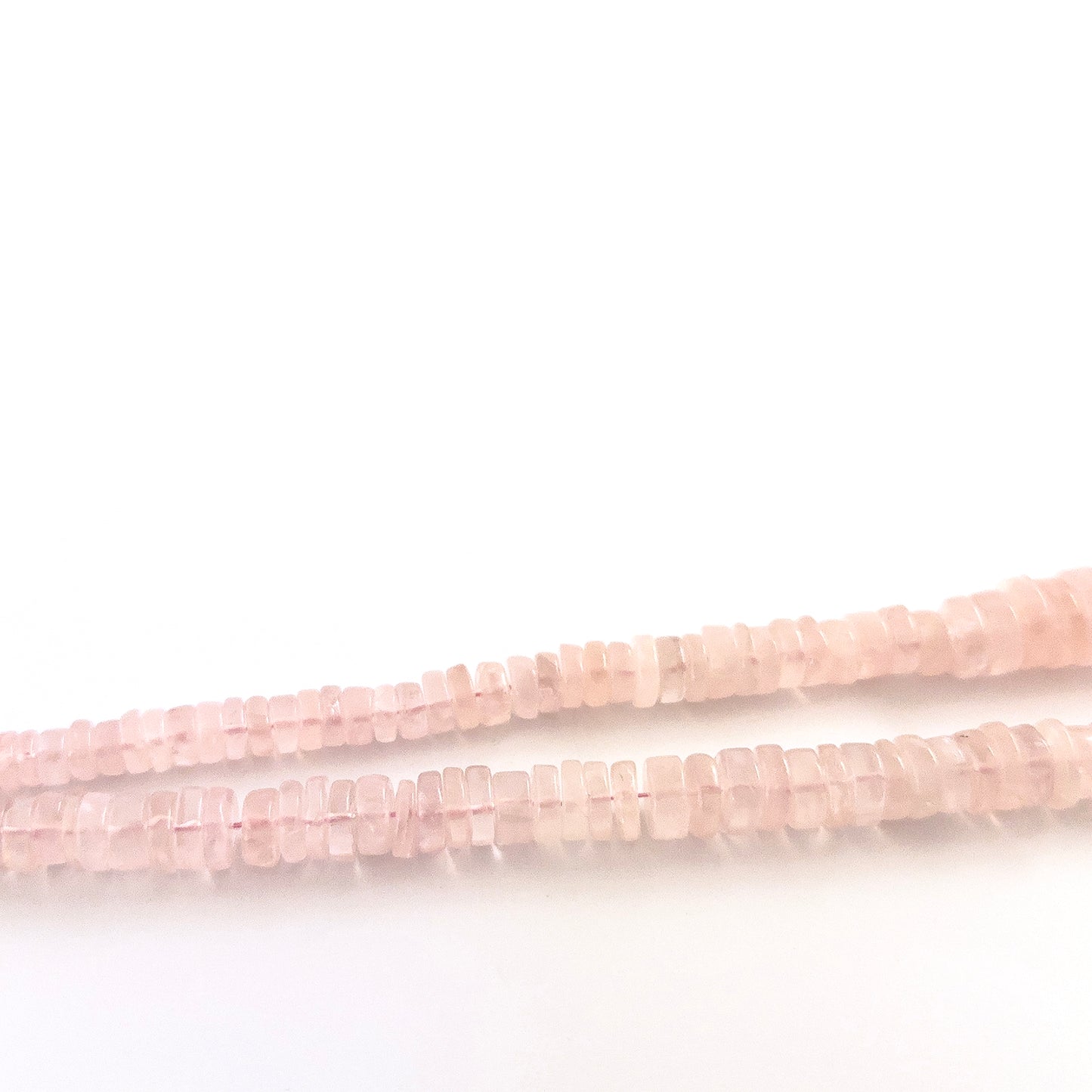 Rose Quartz wheel gemstones sized 5.5–12mm, arranged in a polished strand with varied proportions.