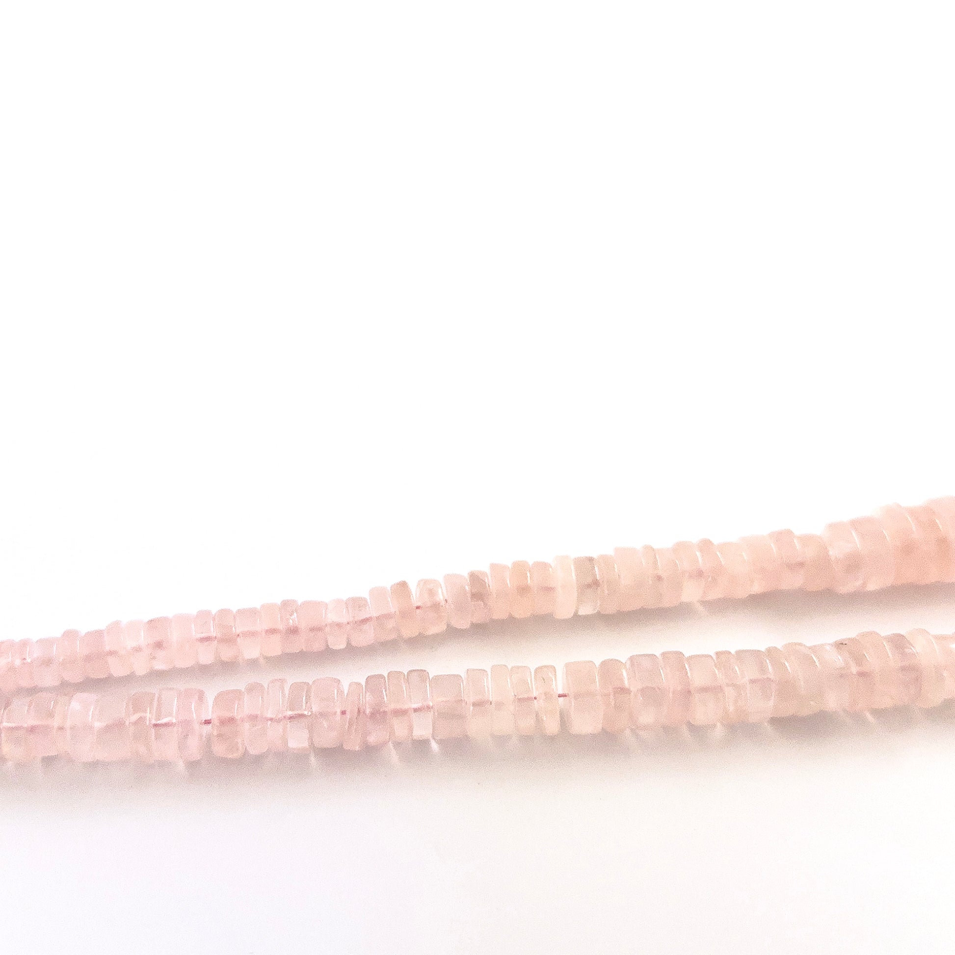 Rose Quartz wheel gemstones sized 5.5–12mm, arranged in a polished strand with varied proportions.