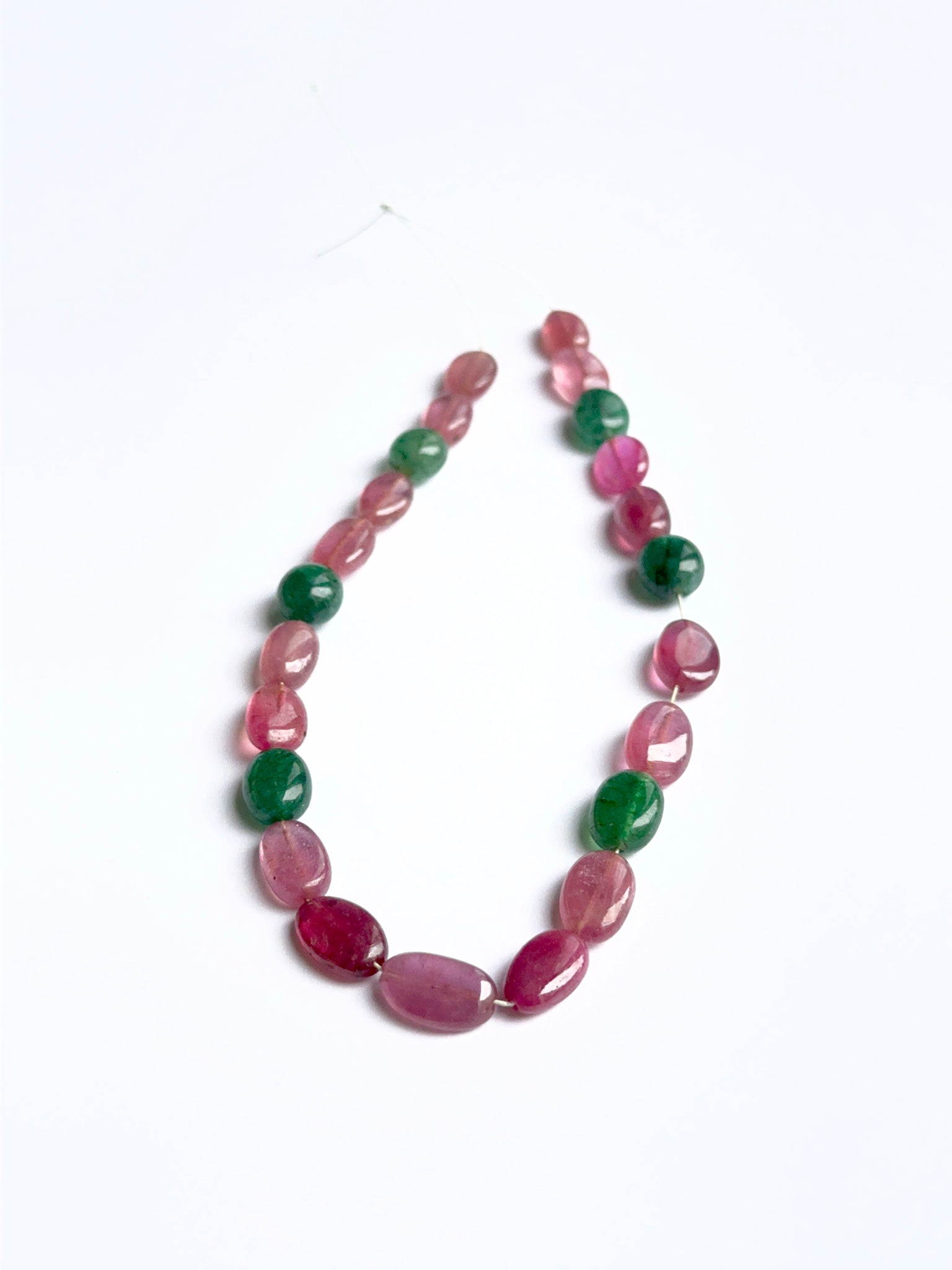 Close‑up of ruby and emerald smooth ovals highlighting their polished finish and gemstone colour.