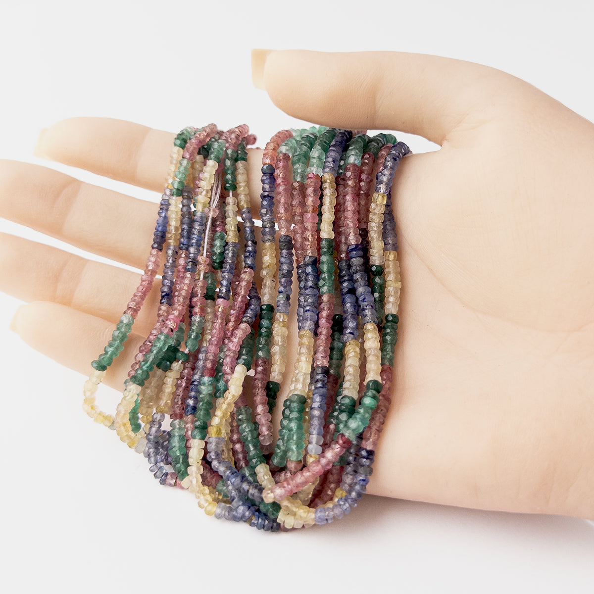 A video person holds delicate strands of Multi Precious Ruby Blue Sapphire Yellow Sapphire and Emerald beads, showcasing their Faceted Rondelle design and sparkle.