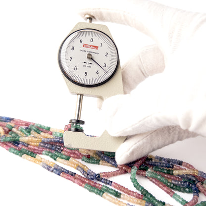 A dial gauge measures the Multi Precious Ruby Blue Sapphire Yellow Sapphire and Emerald Faceted Rondelle 3-3.6mm gemstone.