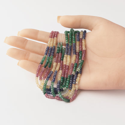 A video person holds delicate strands of Multi Precious Ruby Blue Sapphire Yellow Sapphire and Emerald beads, showcasing their Faceted Rondelle design and sparkle.