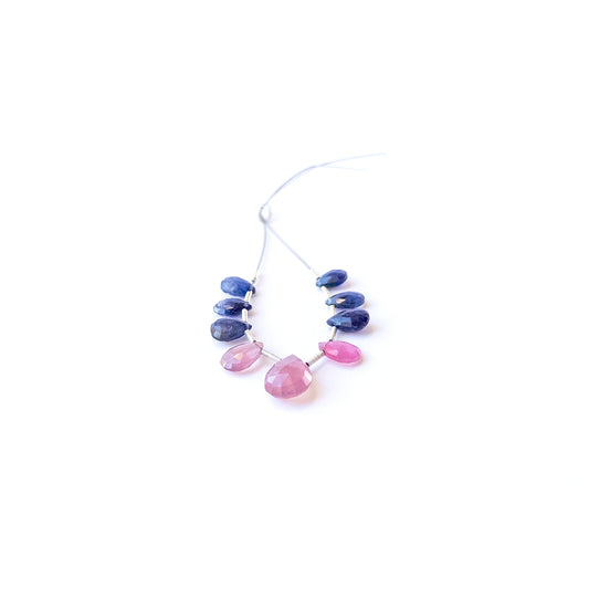 Genuine Ruby and Blue Sapphire faceted briolette gemstone beads arranged to show their vivid sparkle.