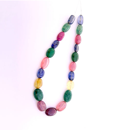 Smooth oval ruby, blue sapphire, yellow sapphire and emerald beads arranged to display uniform shape and rich gemstone hues.
