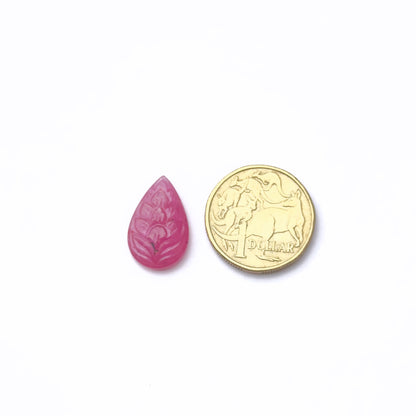 A coin measures the ruby carved 21x13.9mm gemstone.
