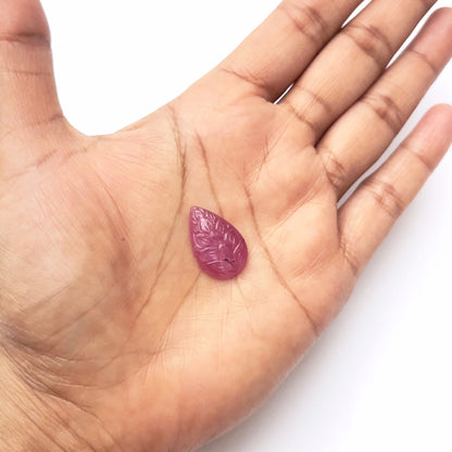 A person holds delicate strands of ruby beads, showcasing their carved design.