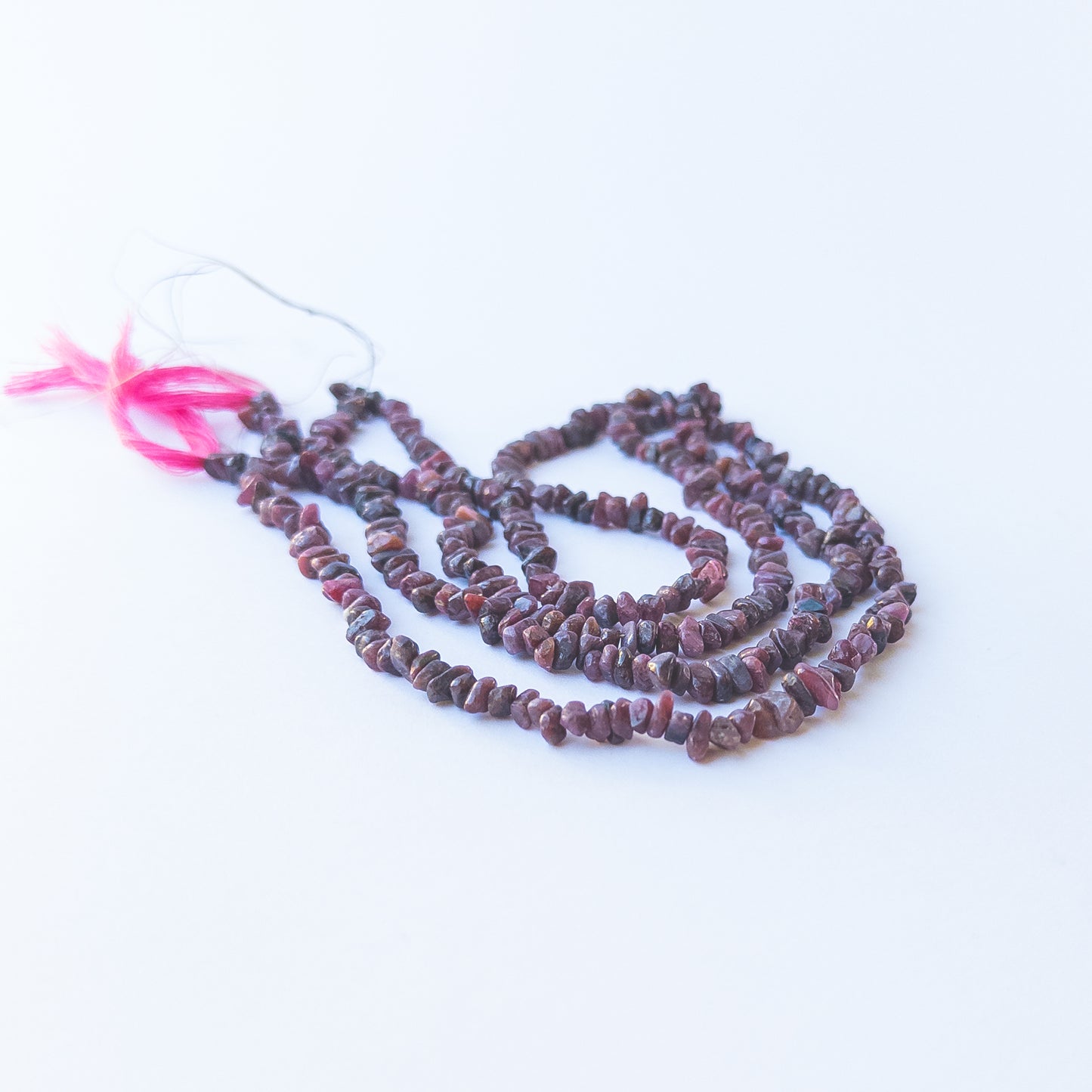 Handmade jewellery components featuring smooth Ruby chip beads in a neatly arranged strand.