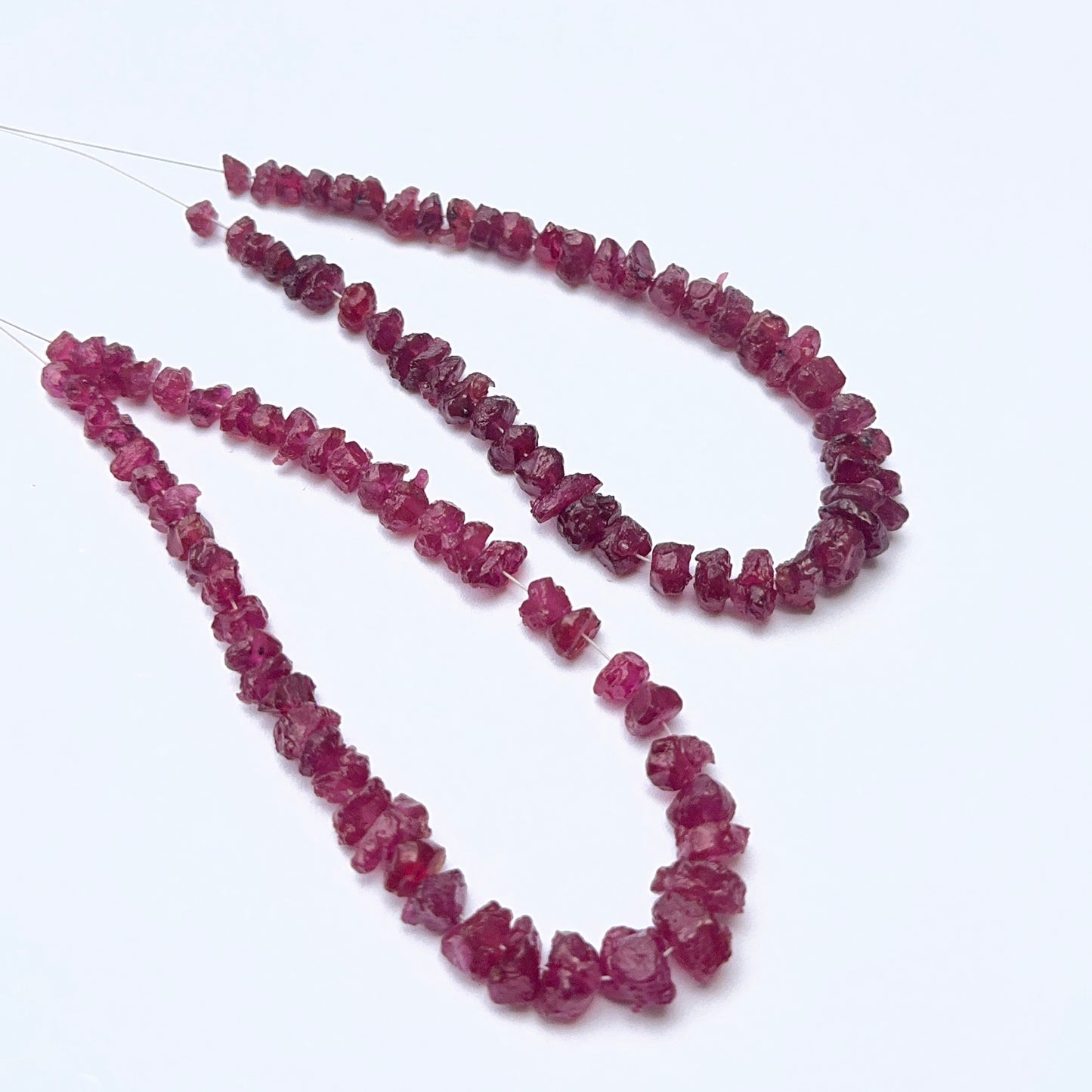 Ruby strand featuring drilled rough ruby beads with raw texture and deep red tones.