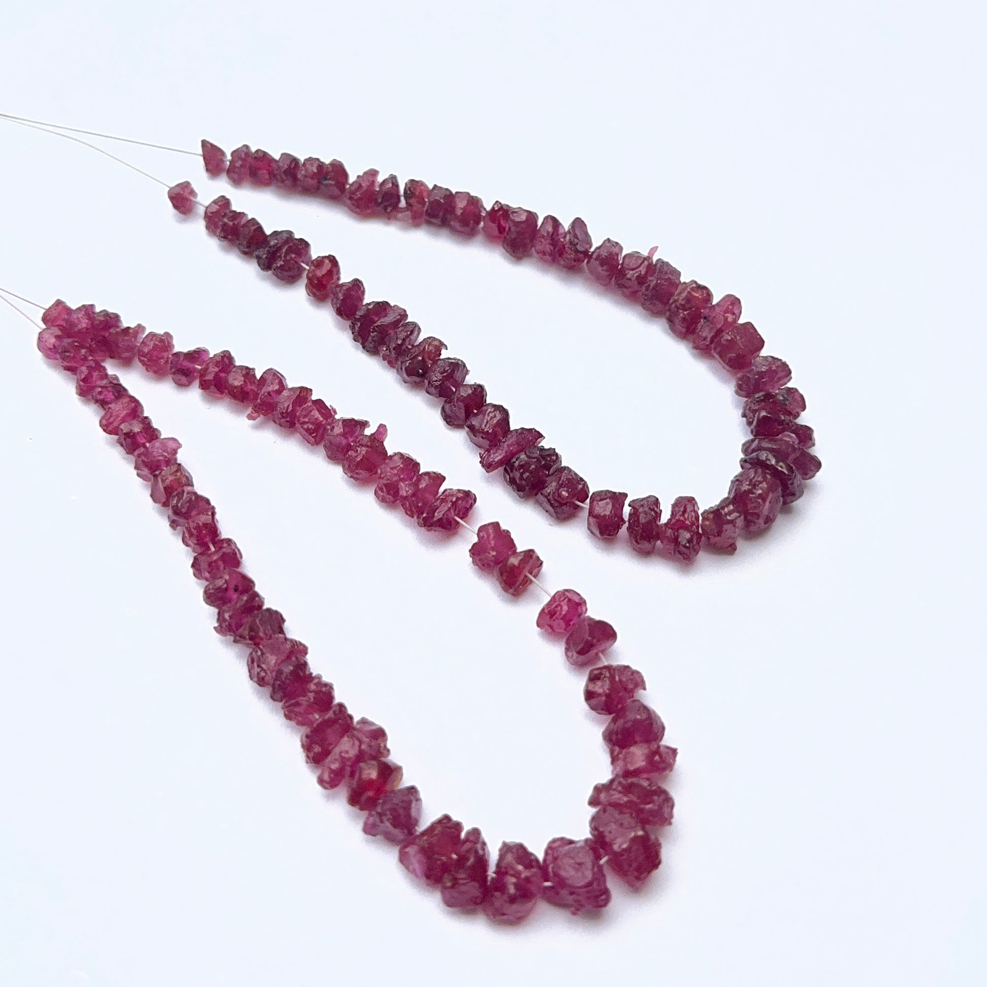 Ruby strand featuring drilled rough ruby beads with raw texture and deep red tones.