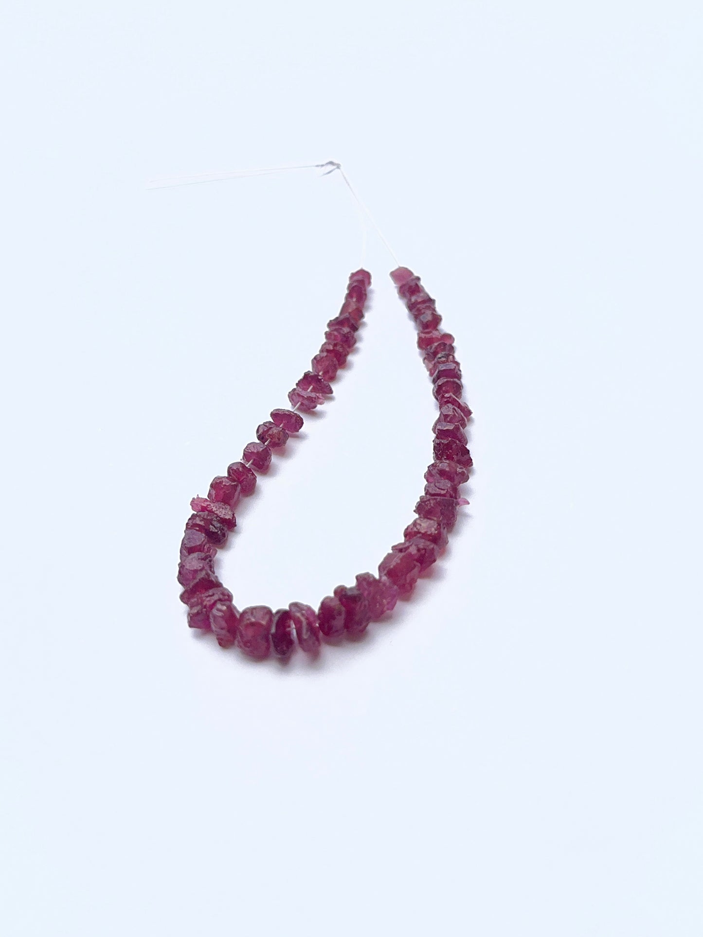 Close‑up of rough ruby beads arranged on a ruby strand.