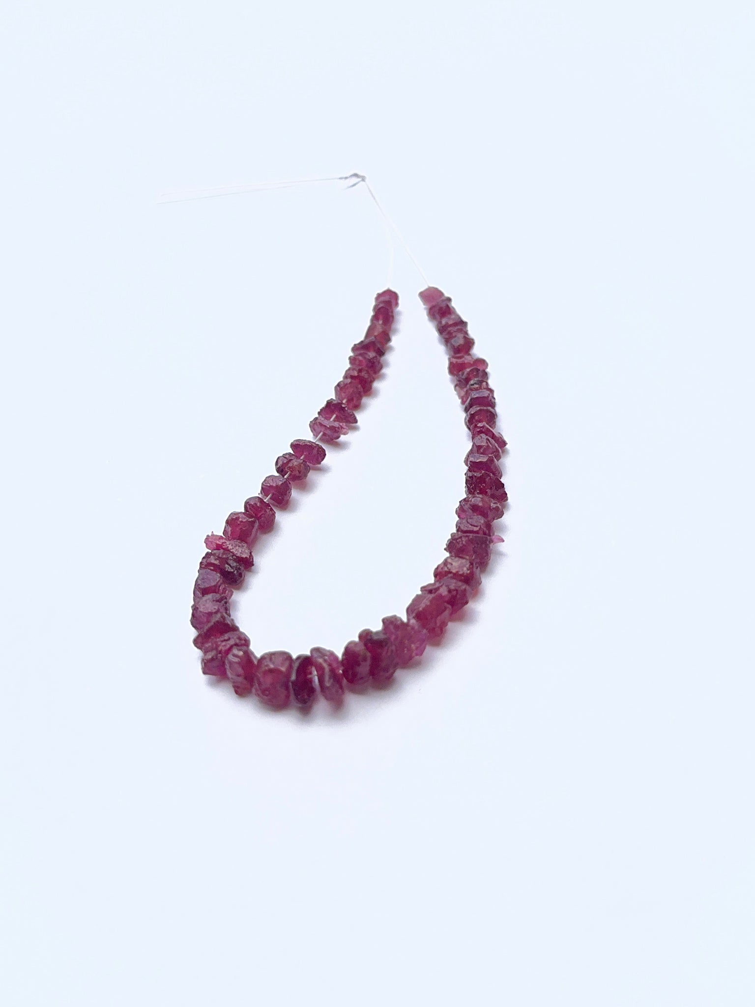 Close‑up of rough ruby beads arranged on a ruby strand.