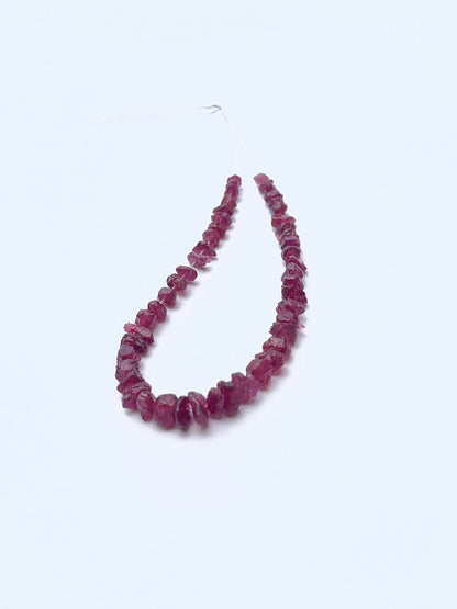 Close‑up of rough ruby beads arranged on a ruby strand.