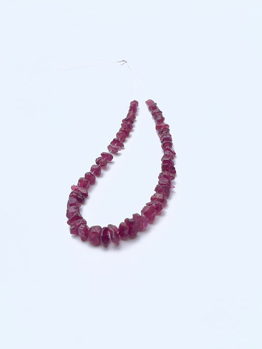 Close‑up of rough ruby beads arranged on a ruby strand.