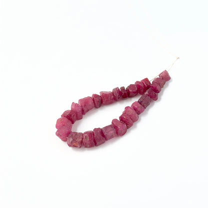Ruby drilled rough beads showing deep red tones and raw textured surfaces.