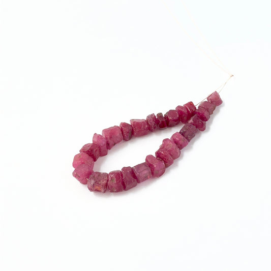 Ruby drilled rough beads showing deep red tones and raw textured surfaces.