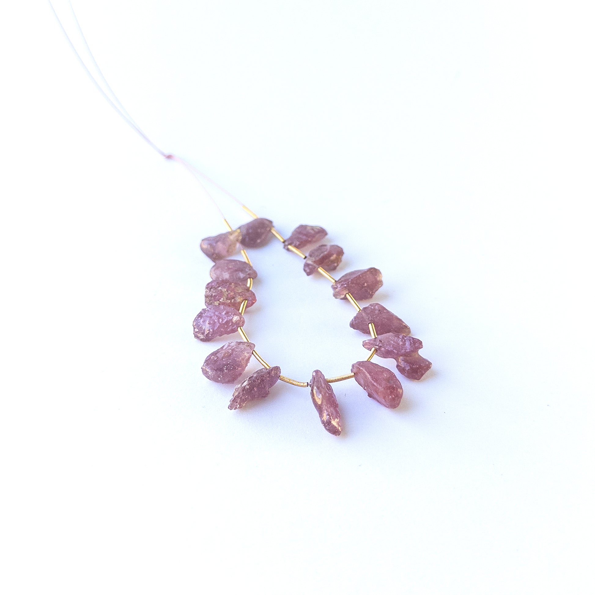 Ruby drilled rough gemstone beads in deep red tones arranged together for handmade jewellery components.