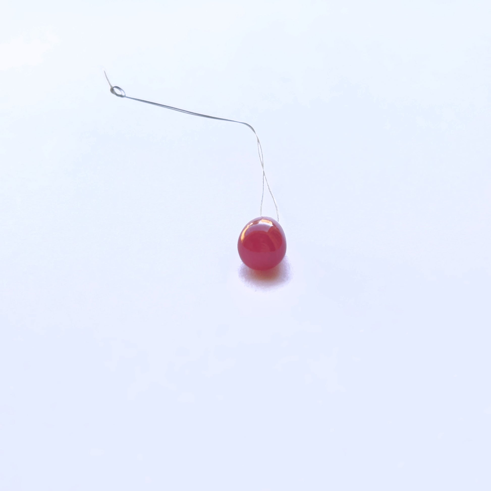 Single ruby stone bead with teardrop shape and glossy shine.