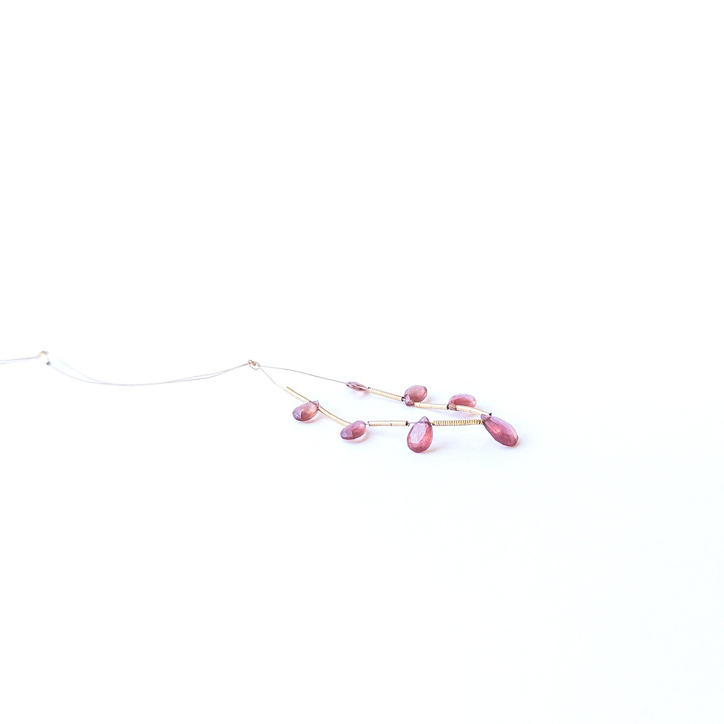 Ruby faceted briolette gemstone beads in deep red hues arranged in a strand for handmade jewellery making.