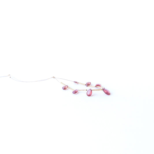 Ruby faceted briolette gemstone beads in deep red hues arranged in a strand for handmade jewellery making.