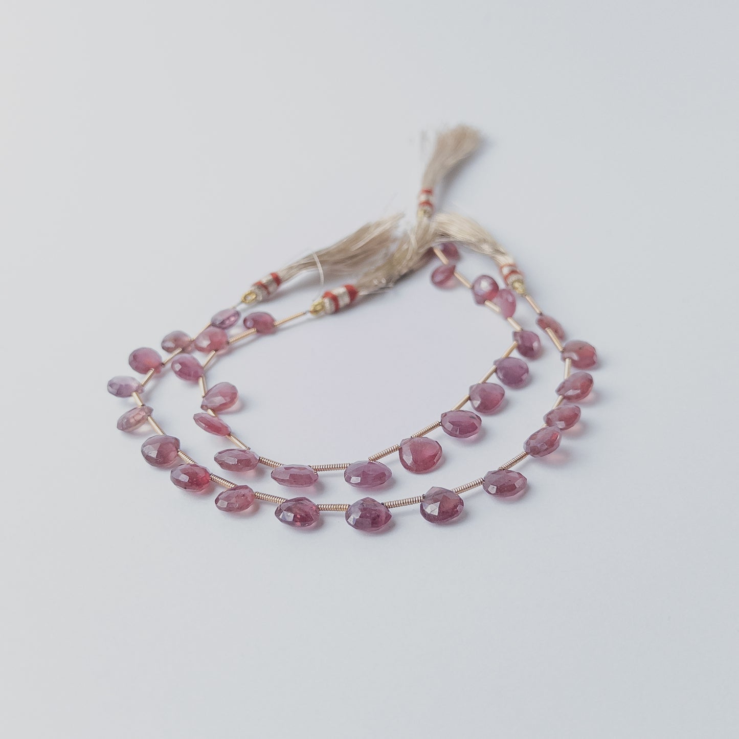 Deep red Ruby gemstone beads in briolette shape, arranged to highlight their natural brilliance.