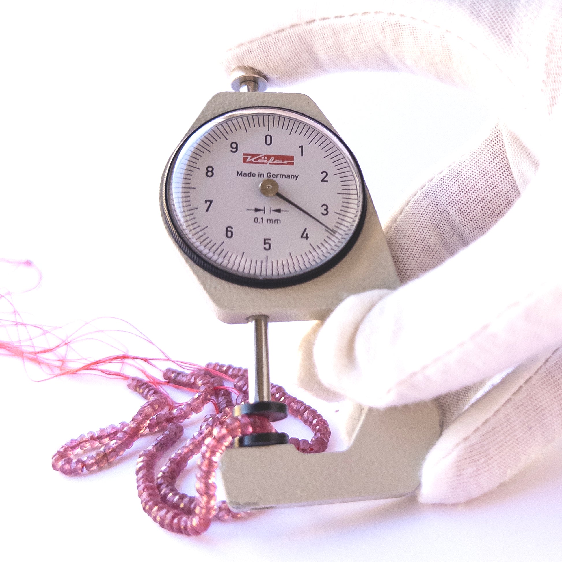 A dial gauge measures the Ruby Faceted Rondelle 3.6–3.8mm gemstone.