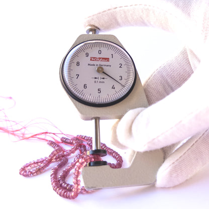 A dial gauge measures the Ruby Faceted Rondelle 3.6–3.8mm gemstone.