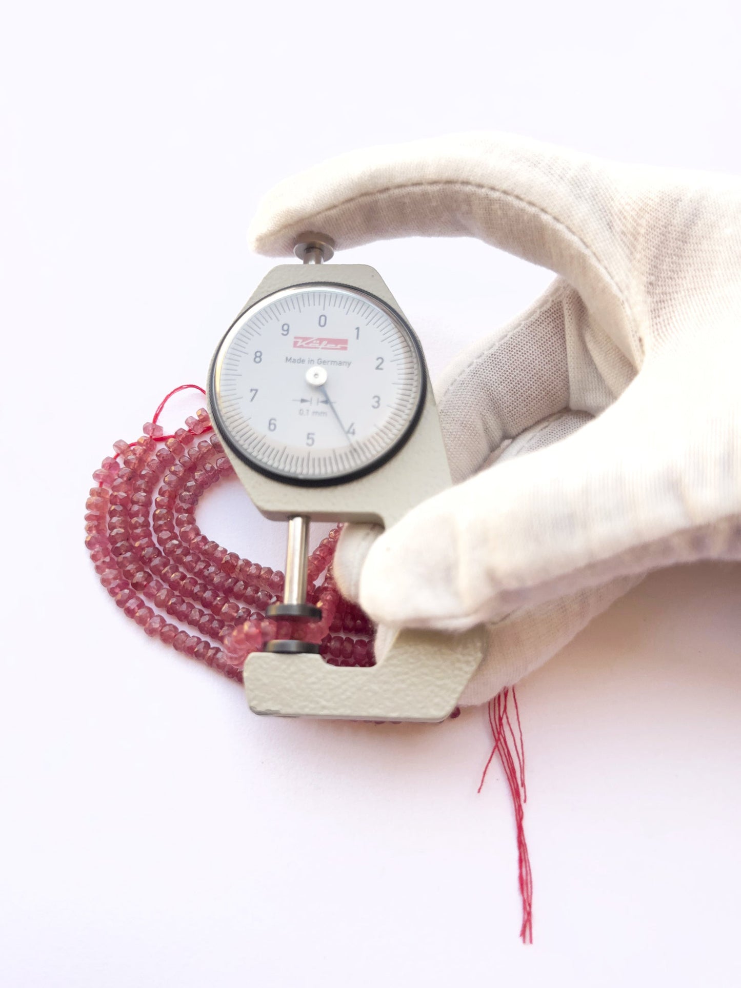 A dial gauge measures the ruby faceted rondelle 4.2–4.5mm gemstone.