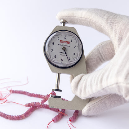 A dial gauge measures the Ruby faceted rondelle 4.2mm gemstone.