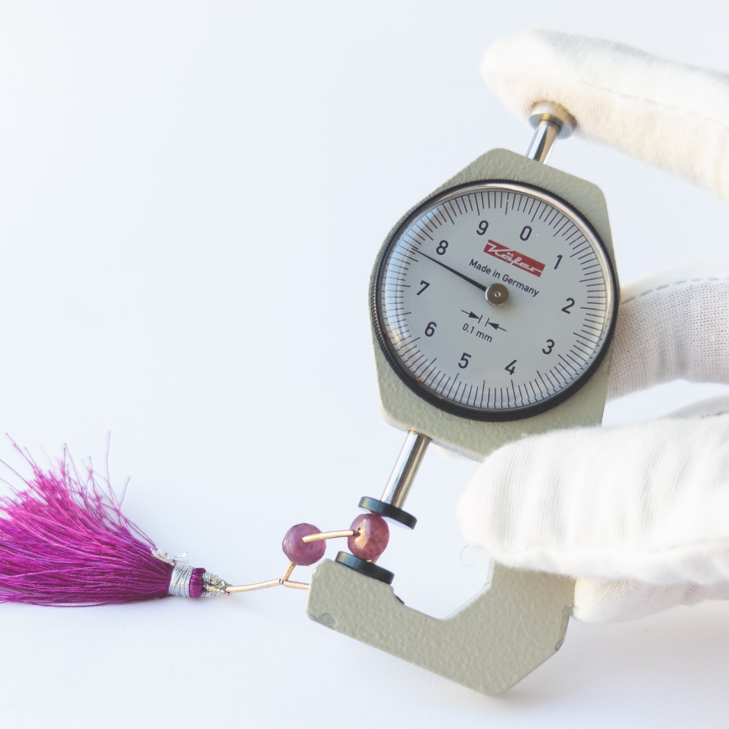 A dial gauge measuring the Ruby faceted rondelle 7.3–7.6mm beads.
