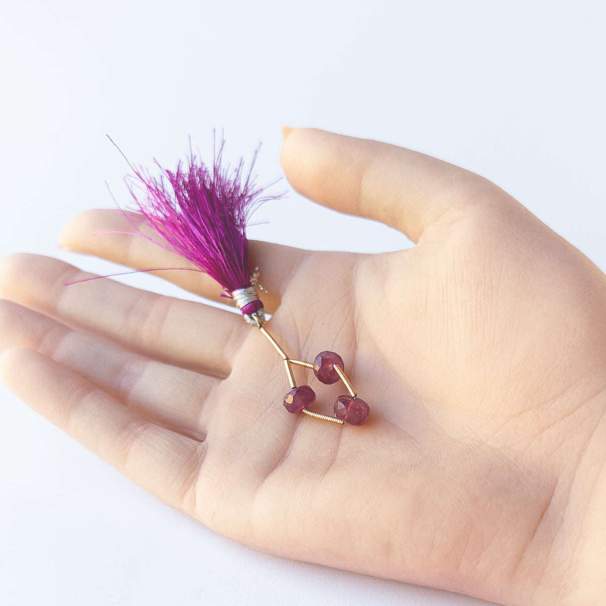 A person holds delicate Ruby beads showcasing their faceted rondelle design.