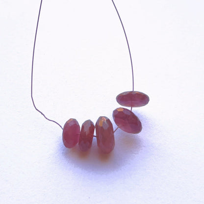Ruby faceted rondelle beads in rich red tones arranged on a string.