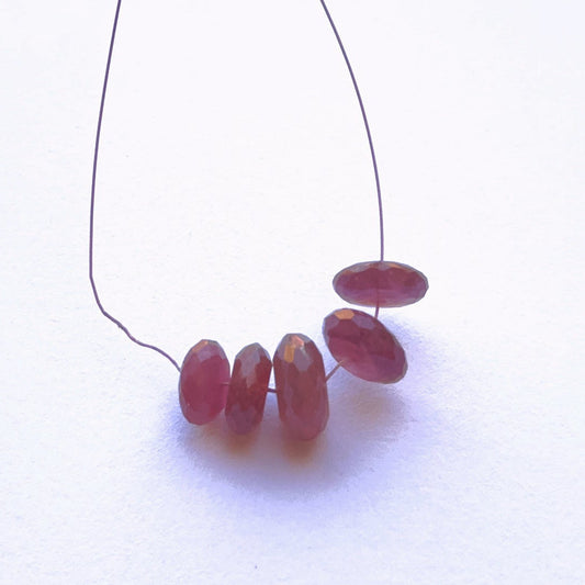 Ruby faceted rondelle beads in rich red tones arranged on a string.