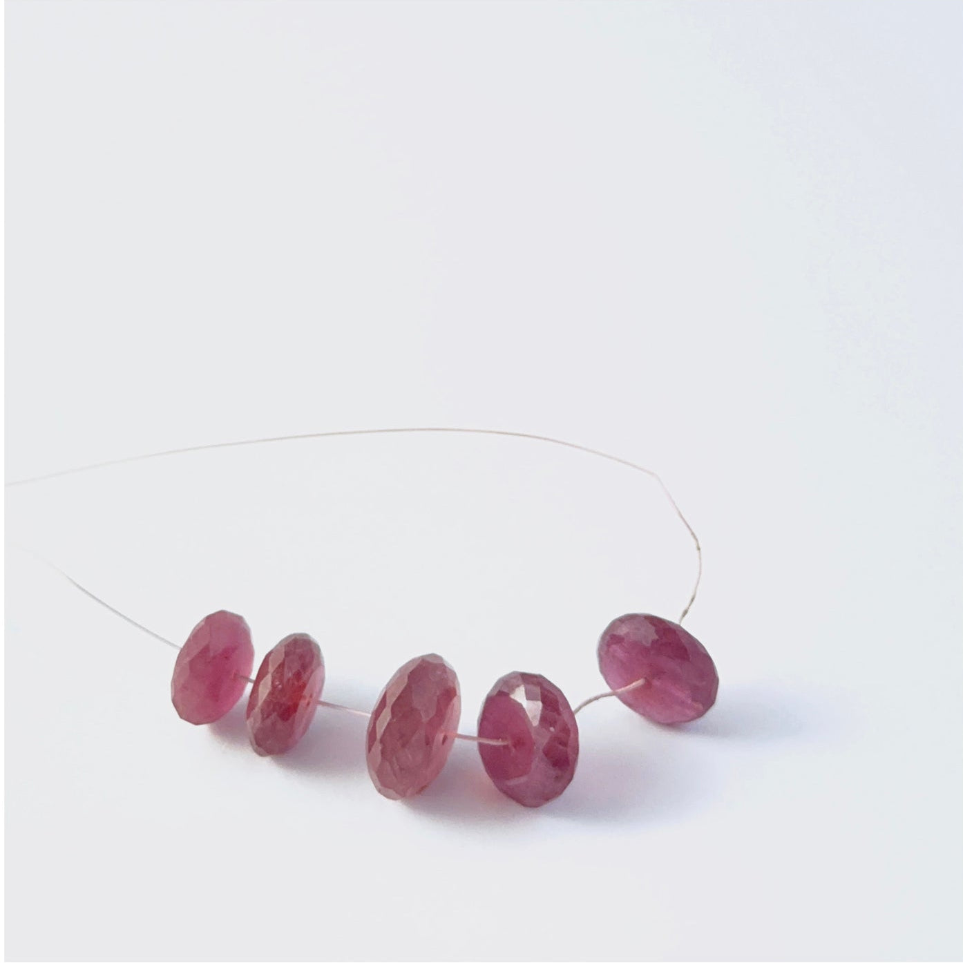 Faceted rondelle Ruby beads arranged neatly, highlighting their polished finish and handmade jewellery component quality
