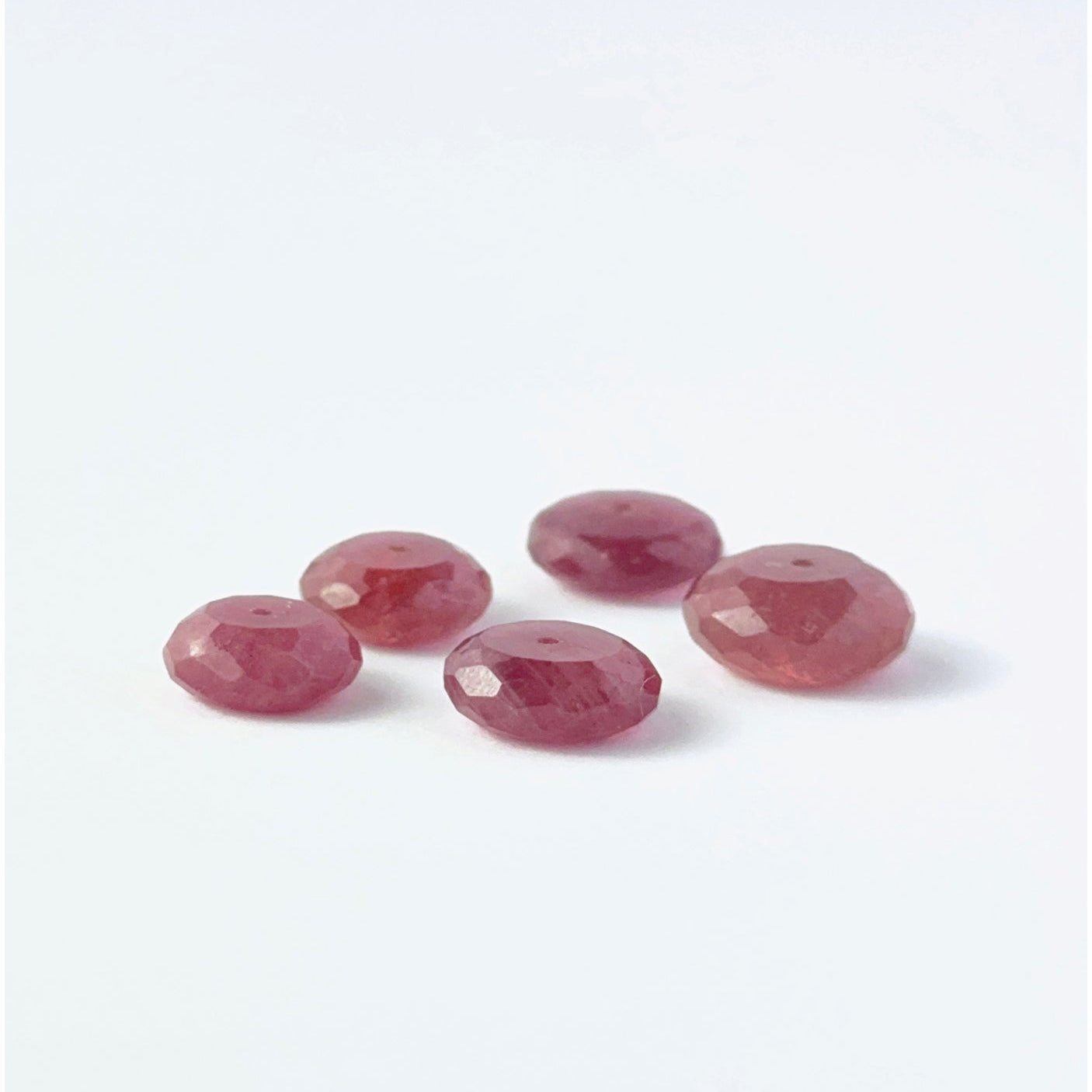 Delicate Ruby beads, showcasing their faceted rondelle design.