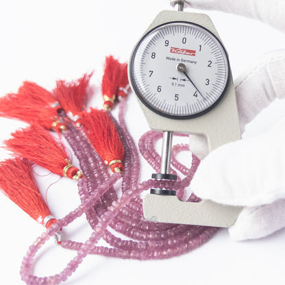 A dial gauge measures the Ruby faceted rondelle 3–3.7mm bead size gemstone.