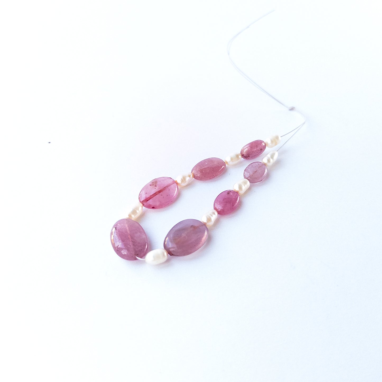 Close‑up of Ruby and freshwater pearl beads highlighting polished surfaces and contrasting textures.