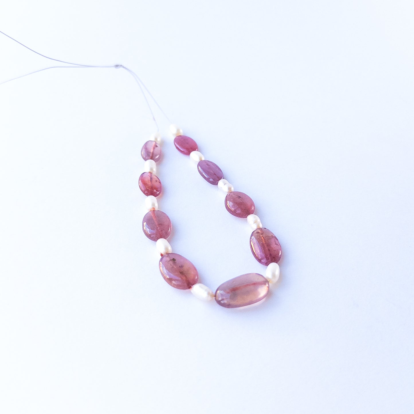 Ruby and freshwater pearl smooth oval beads shown as 19 pieces totalling 51 carats for jewellery making.