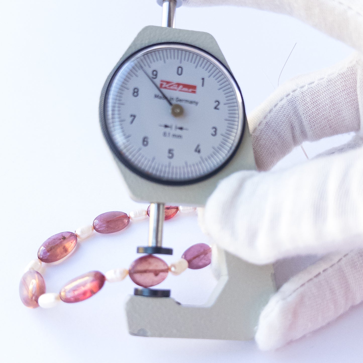 A dial gauge measures the Ruby smooth oval 7–9.5mm gemstones and baroque pearls.