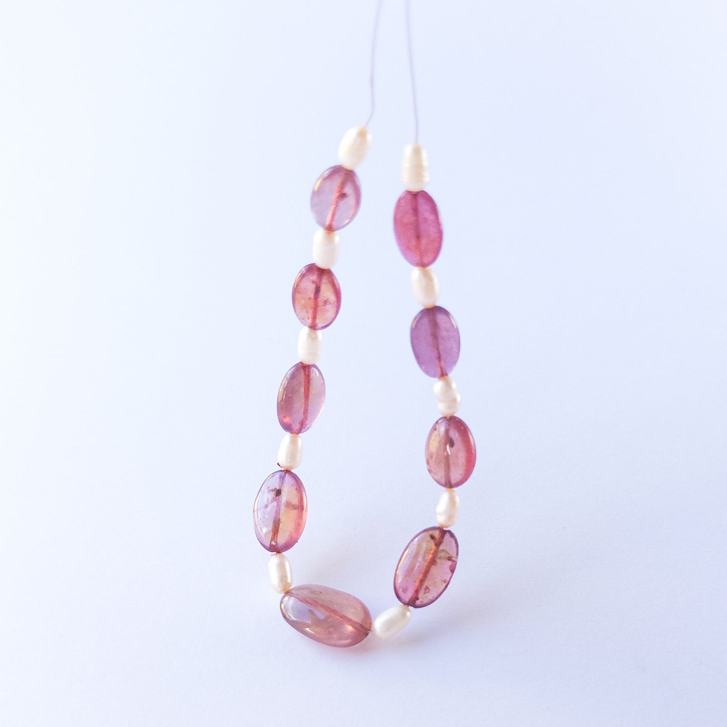 Ruby and freshwater pearl beads highlighting polished surfaces and contrasting textures.