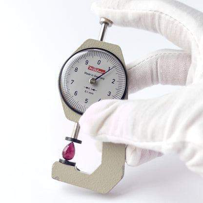 A dial gauge measures the Ruby pear‑cut cabochon 11mm × 7.4mm gemstone.